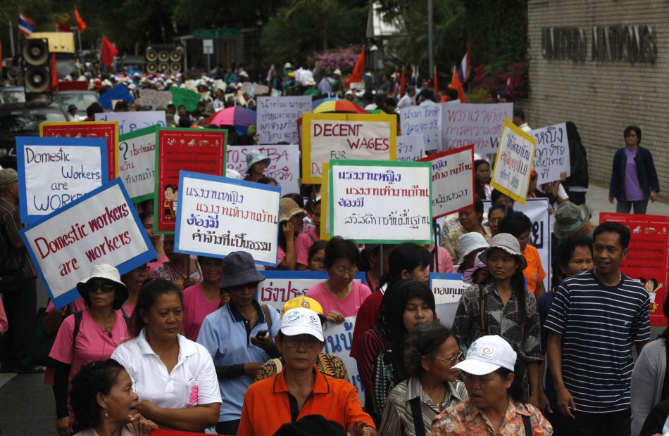 Female workers hold signs as they gather to mark International Womens Day outside the United Nations building in Bangkok