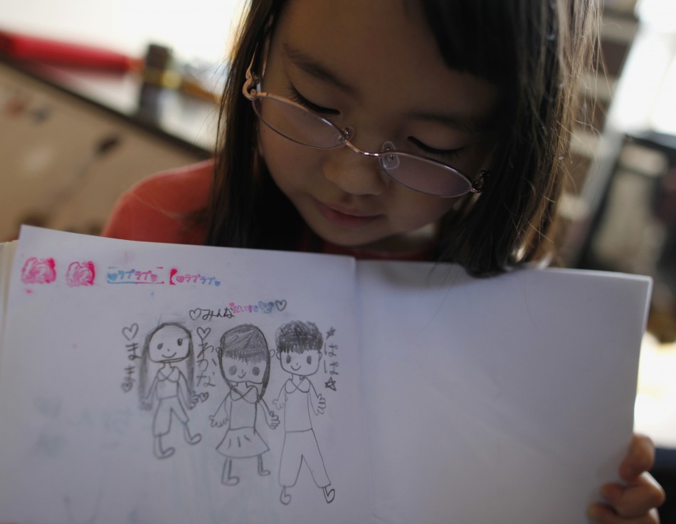 Wakana Kumagai, 7, holds her illustration of her family in Higashimatsushima