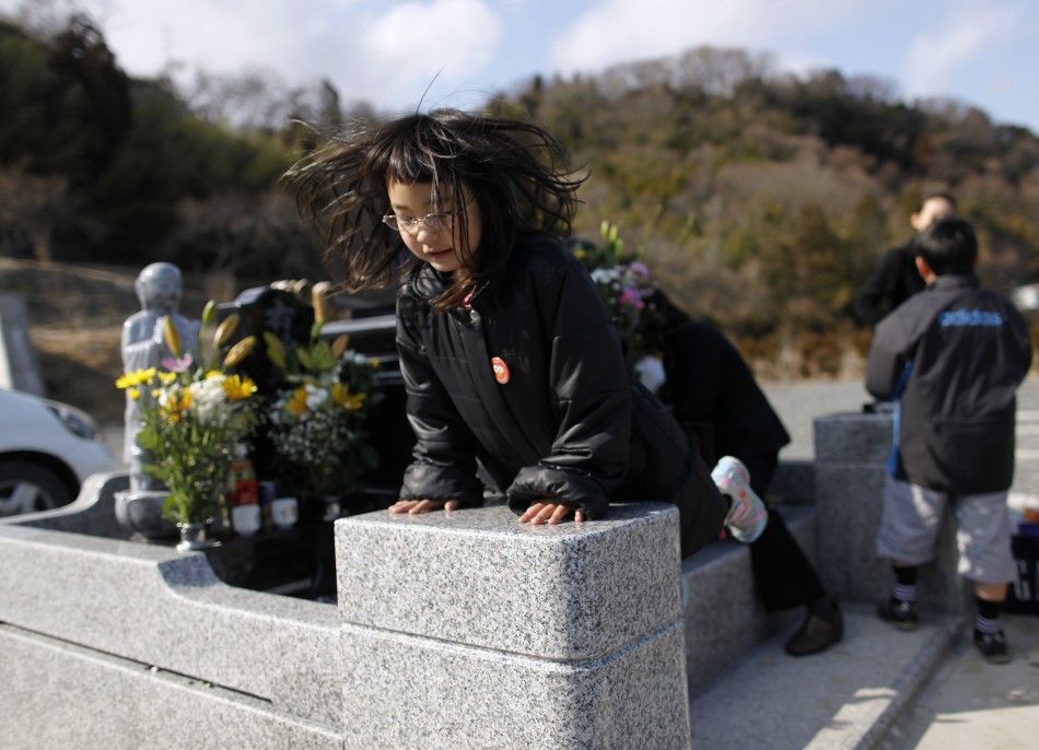 umagai, jumps on the grave of her father, who was killed by the tsunami, in Higashimatsushima, Miyagi prefecture