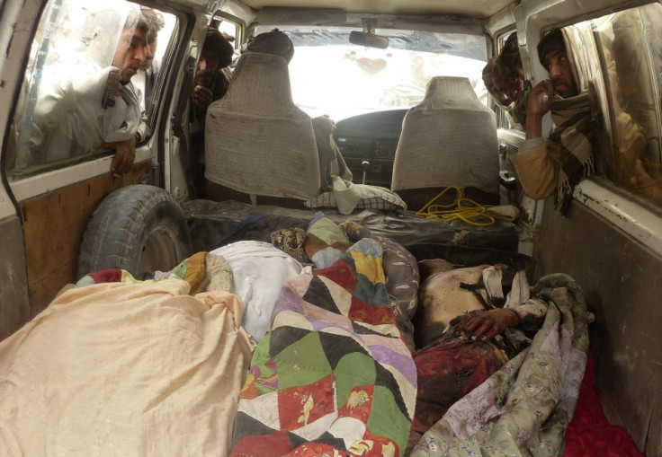 Afghan men look over the dead bodies of people killed by coalition forces in Kandahar province
