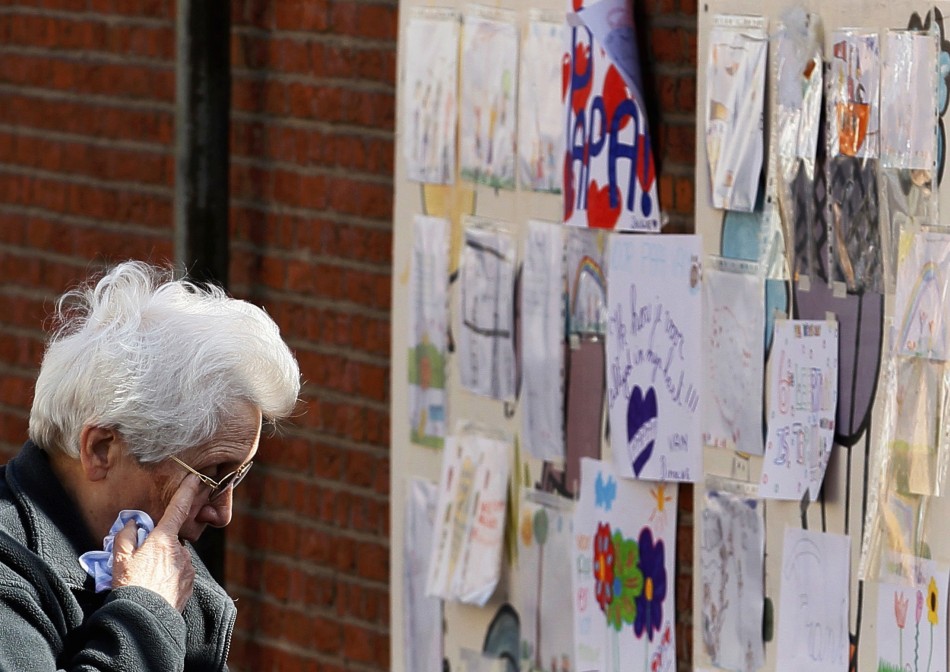 A woman, paying tribute to the victims of a bus crash in Switzerland, wipes her eyes while looking at drawings outside St Lambertus school in Heverlee