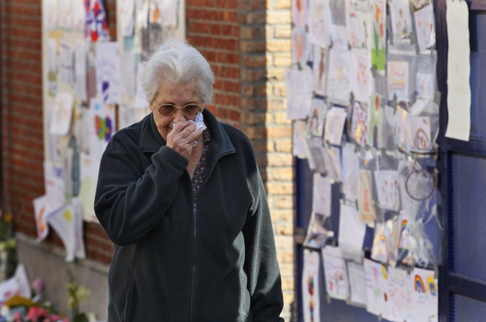 A woman, paying tribute to the victims of a bus crash in Switzerland, wipes her eyes outside St Lambertus school in Heverlee