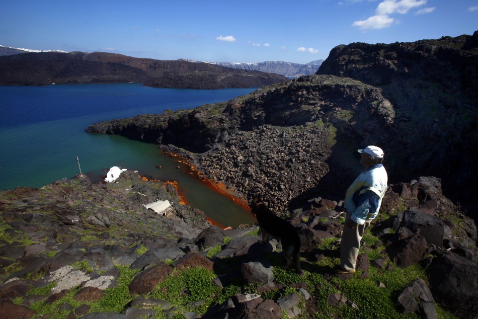 Sostis walks his dog Plato on the volcanic islet of Palaia Kameni located in the caldera of Santorini