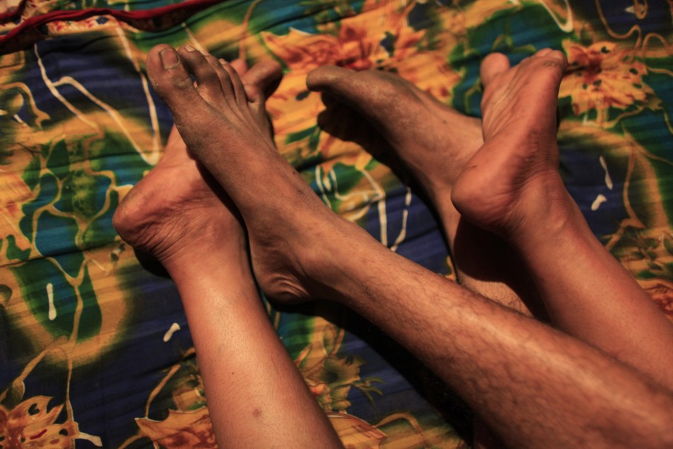 Feet belonging to Hashi, a prostitute, and Babu, her husband, are seen inside her small room at Kandapara brothel in Tangail, a northeastern city of Bangladesh