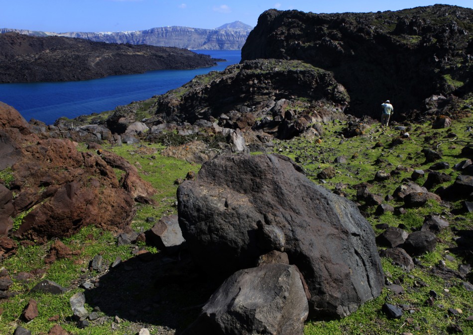 Sostis walks atop the volcanic islet of Palaia Kameni located in the caldera of Santorini