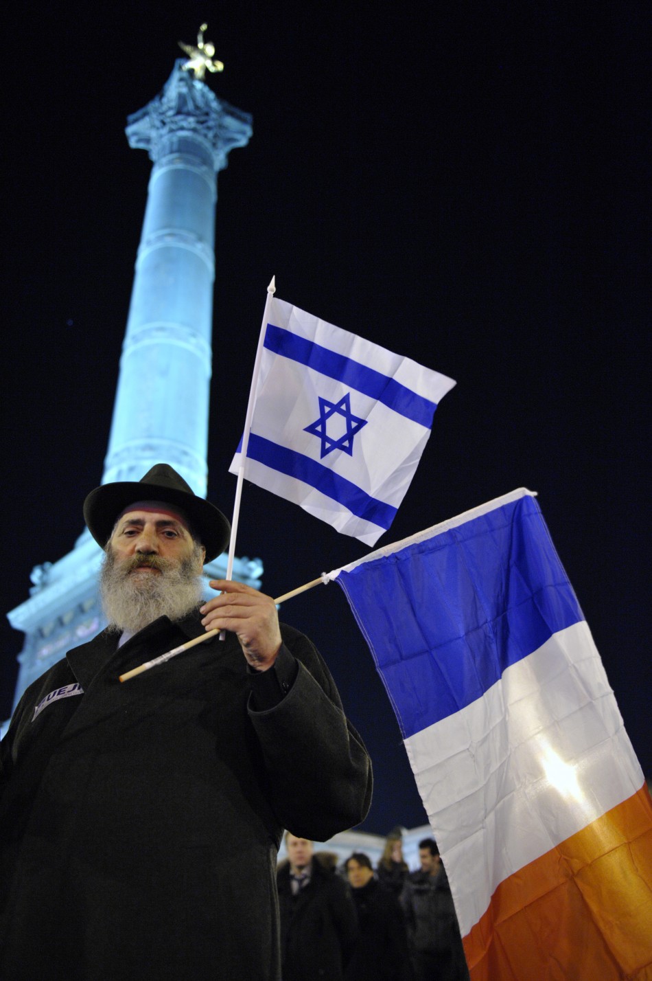 A man holds French and Israeli flags