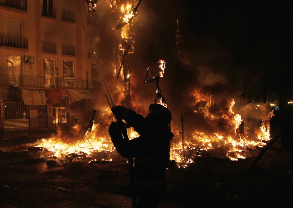 A firefighter sprays water to control the burning of effigies during the finale of Fallas festival in Valencia