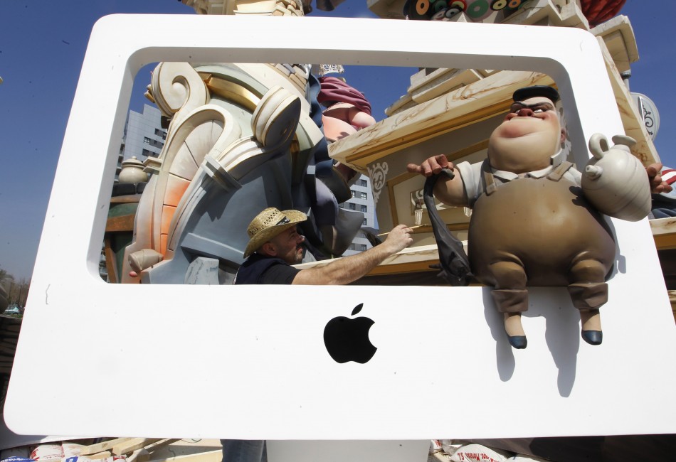 A craftsman puts finishing touches on a figure sitting on a representation of an Apple computer ahead of the quotFallasquot festival in Valencia