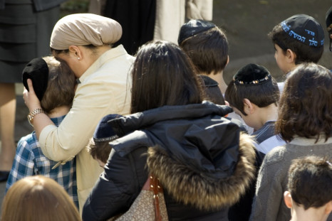 A teacher comforts a school child as they observe a minute of silence at a Jewish school in Paris