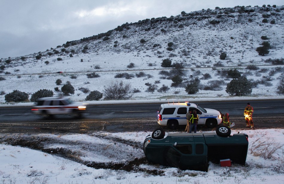 Firefighters and police officers stand near a pick-up truck that rolled on its side after the driver lost control along Interstate-17 in Yavapai County