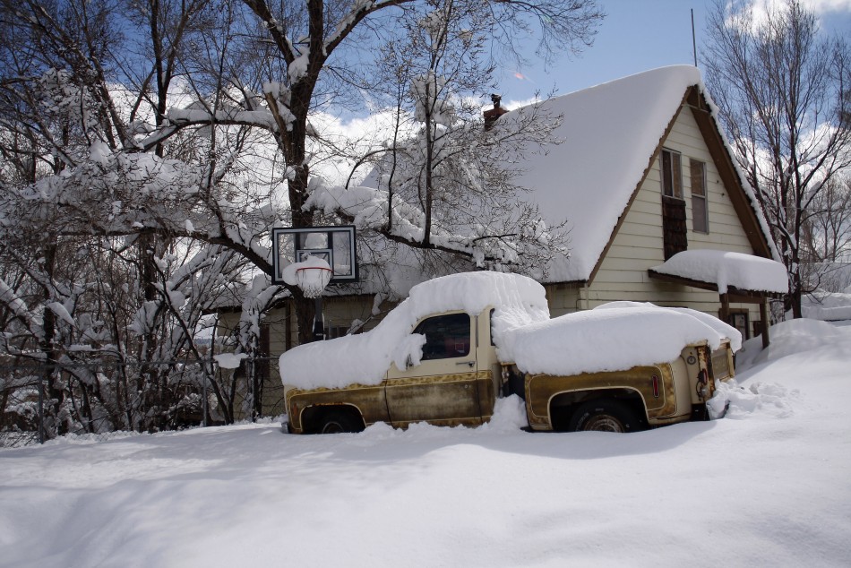 Snow blankets a pick-up truck and a house after a winter storm in Flagstaff