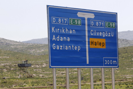 A Turkish soldier stand in a watchtower with a road sign showing directions to Cilvegozu border crossing and Syrian city of Aleppo in the town of Reyhanli in Hatay province on the Turkish-Syrian border