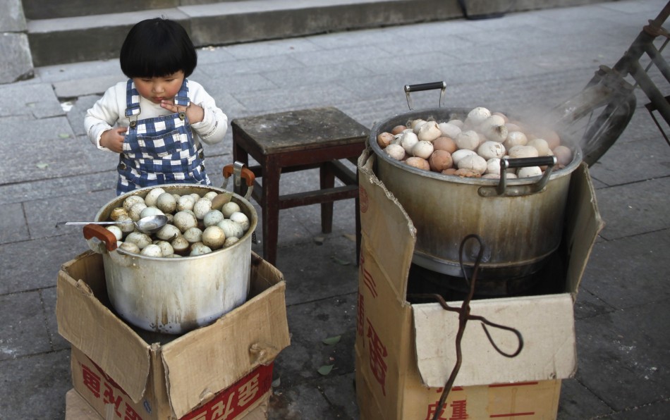 A girl looks at a pot of regular hard-boiled eggs, next to a pot cooked in boys urine in Dongyang