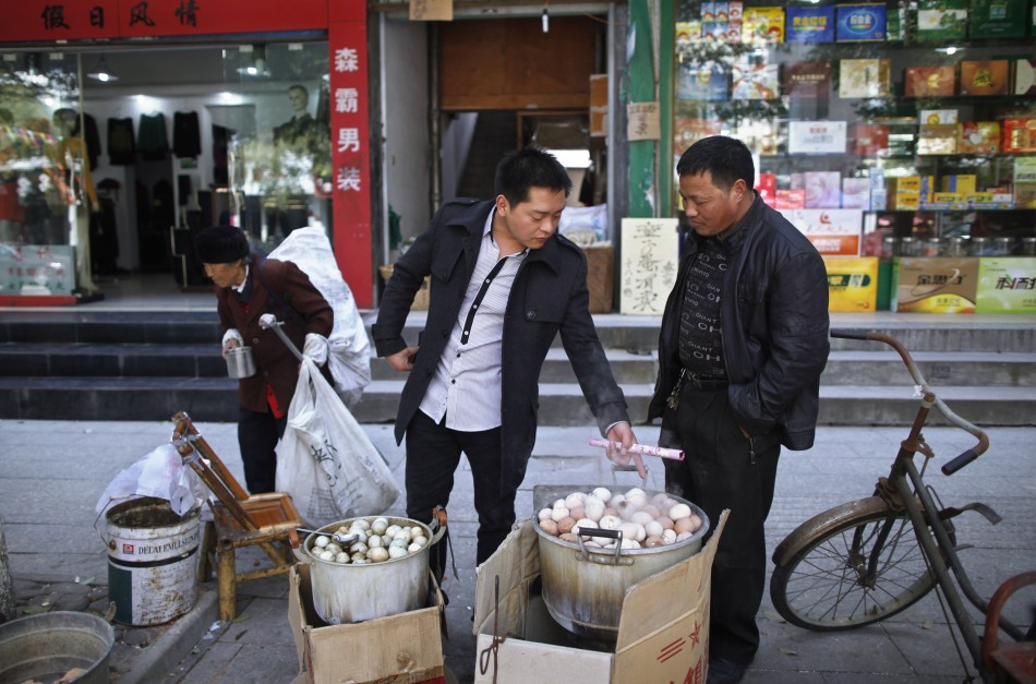 Vendor Ge Yaohua looks at a customer pointing at a pot of hard-boiled eggs cooked in boys urine in Dongyang
