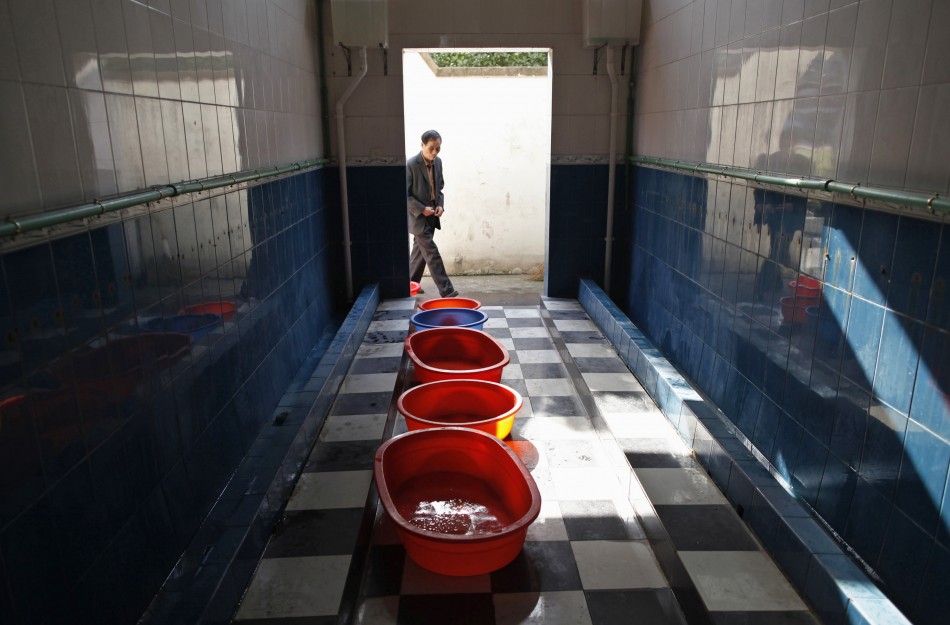 A man walks into a primary school toilet where containers are placed to collect urine passed out by boys, in Dongyang