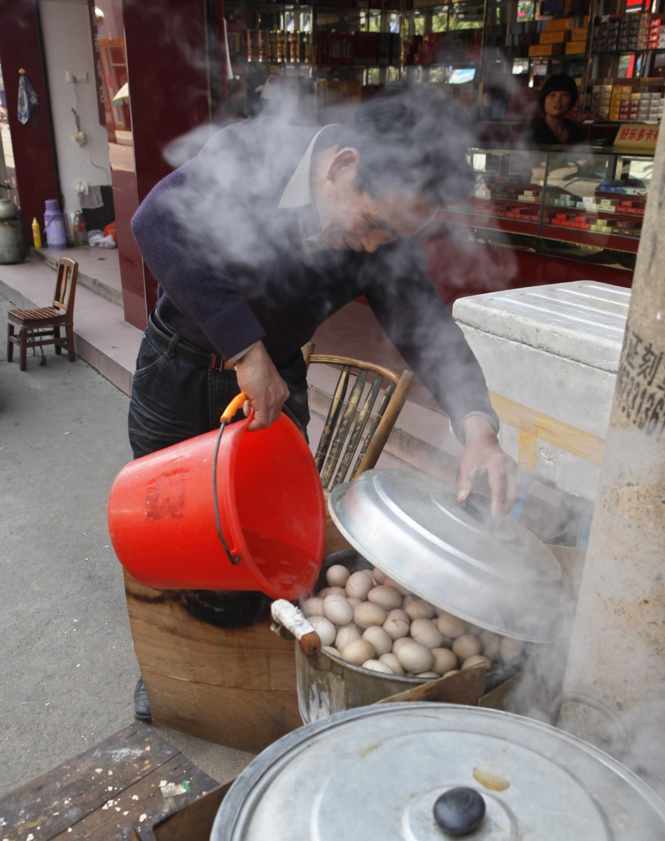 A vendor pours a bucket of boys urine into a pot of hard-boiled eggs at his stall in Dongyang