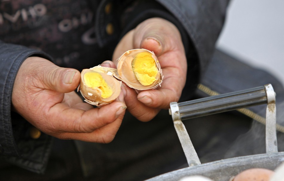 Vendor Ge Yaohua shows the inside of a hard-boiled egg cooked in boys urine at his stall in Dongyang