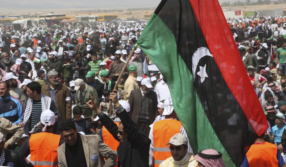 A man holds up a Libyan flag during joint activities near the Jordanian side of the Jordan River to mark Land Day