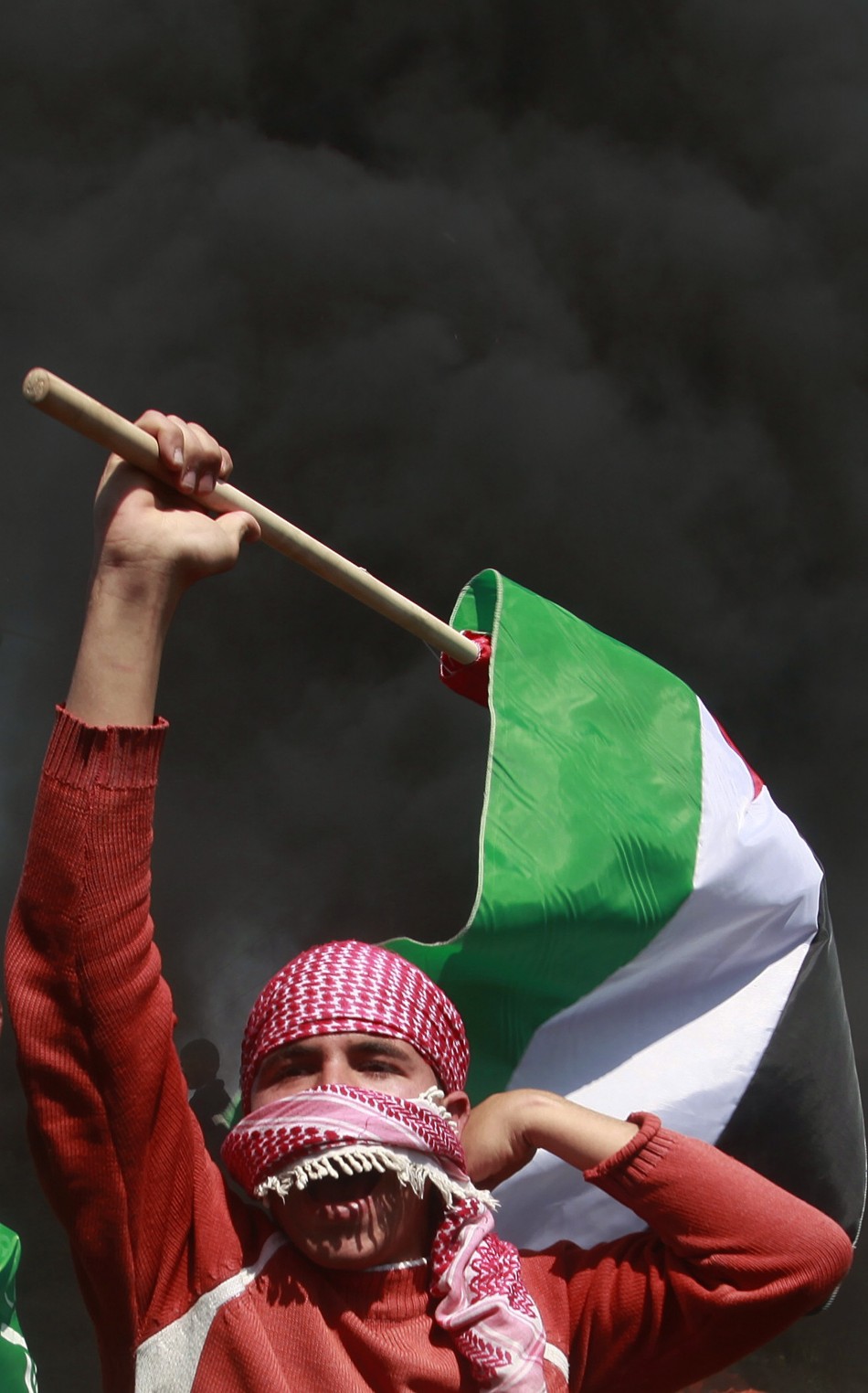A Palestinian protester holds a flag during a protest marking Land Day, near the border between Israel and the northern Gaza Strip