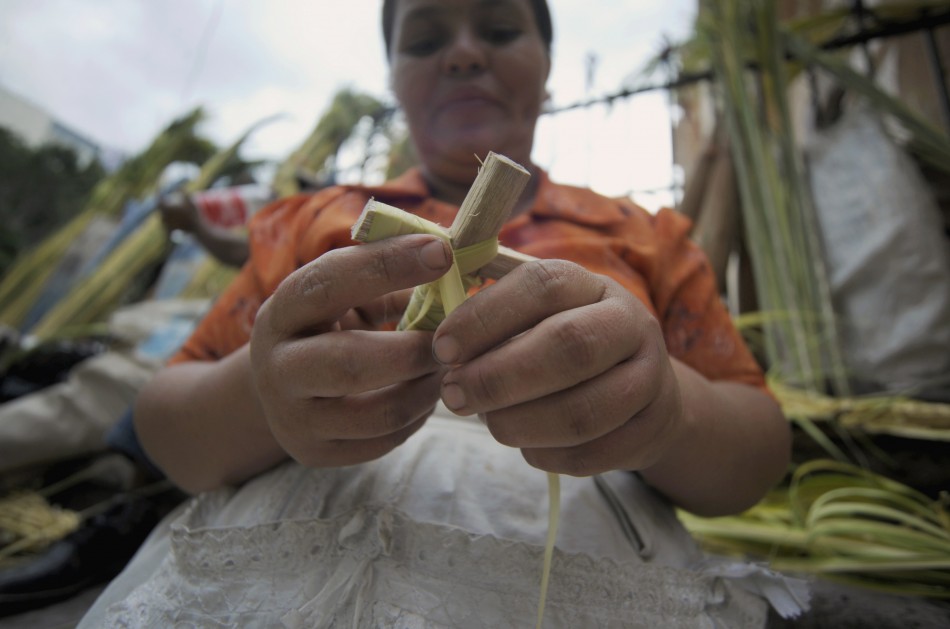 A woman makes a cross for sale outside a church in Tegucigalpa