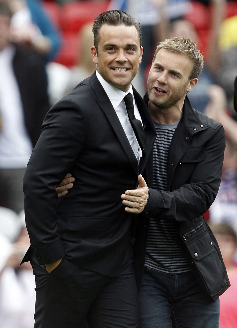 British singer Robbie Williams L walks onto the pitch with band mate Gary Barlow