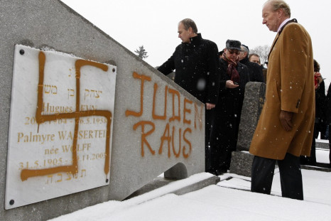 France's Interior Minister Hortefeux walks next to a tombstone desecrated by vandals with Nazi swastikas and the Slogan "Jews out", in the Jewish Cemetery of Cronenbourg