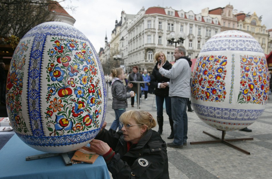 A woman paints a giant Easter egg at a traditional Easter market at the Old Town Square in Prague