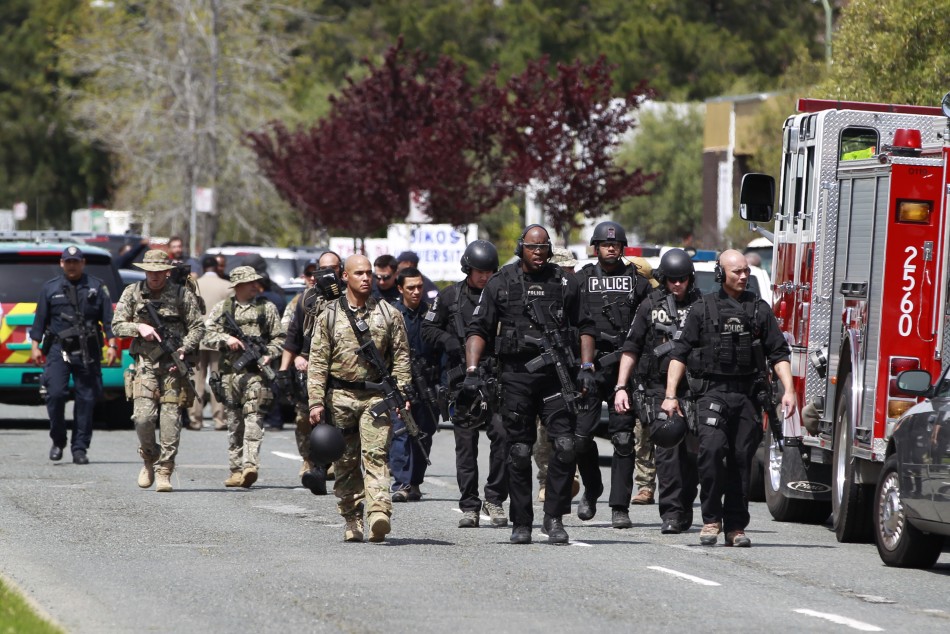 Police officers walk on Edgewater Drive after a shooting at Oikos University in Oakland