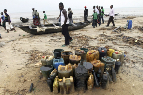 Villagers from Orobiri village walk past jerry cans of crude oil collected from a loading accident by Royal Dutch Shell on the Atlantic coast of Nigeria