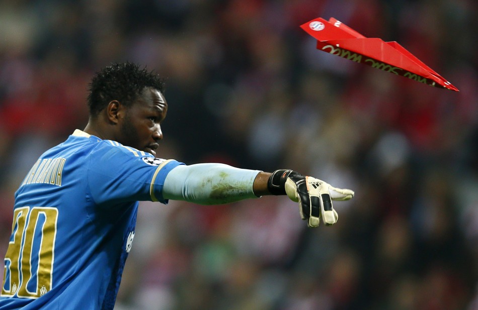 Goalkeeper Steve Mandanda of Olympique Marseille throws away a paper made plane thrown at him by Bayern Munich supporters during their Champions League quarter-final second leg soccer match in Munich