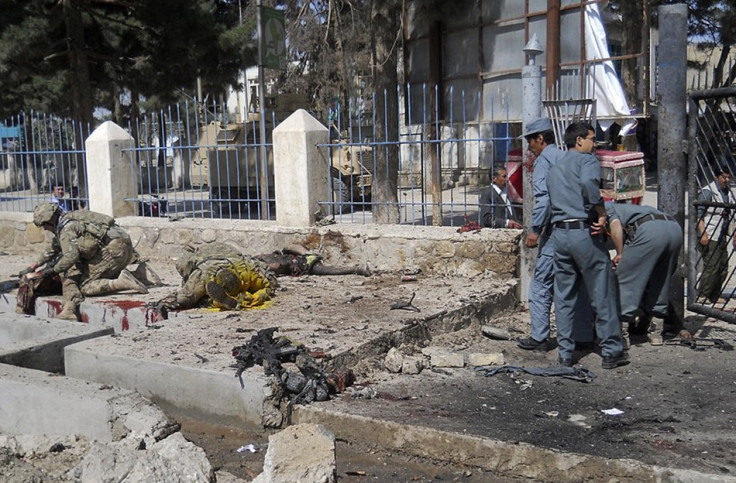 Afghan policemen and NATO troops inspect the site of a suicide attack in Faryab province