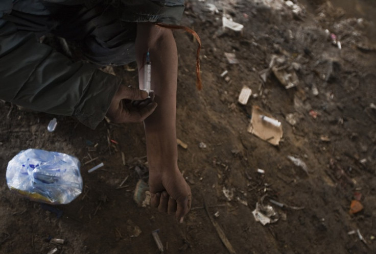 An Afghan drug addict injects himself under a bridge inhabited by fellow addicts in Kabul