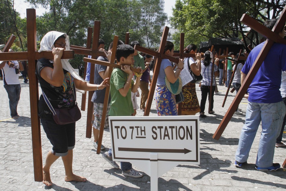Catholic faithful carry crosses as they make their way to one of the Stations of the Cross while doing the Visita Iglesia on Maundy Thursday at a church in Quezon City
