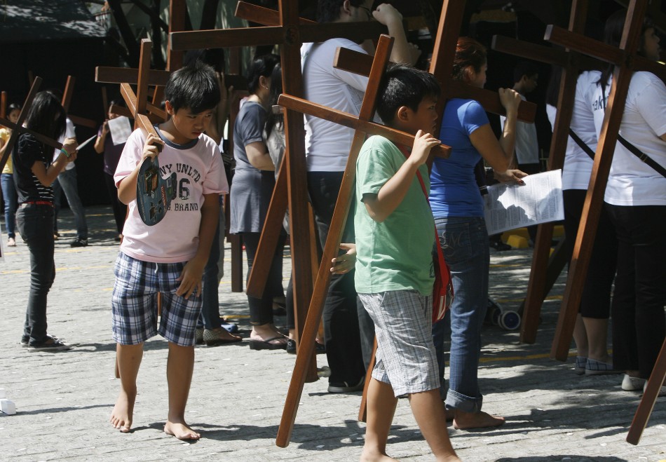 Children carry cross as they join their family members to pray at one of the Stations of the Cross while doing Visita Iglesia on Maundy Thursday at a church in Quezon City