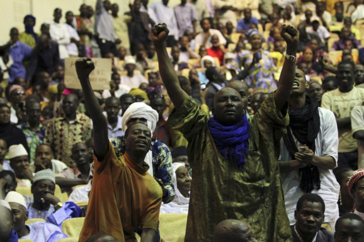 Malians, who originate from the north, pump their fists in the air during a meeting in Bamako