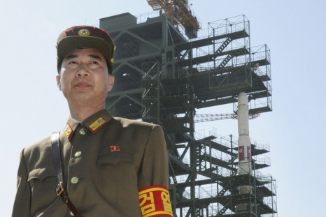 Soldier stands guard in front of Unha-3 rocket at West Sea launch site near Pyongyang