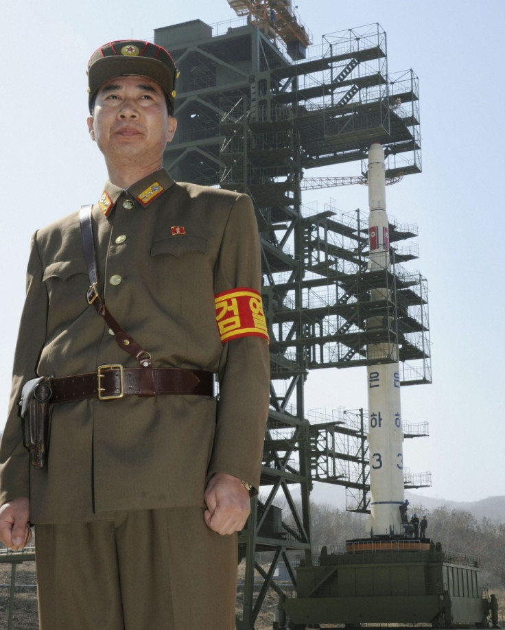 Soldier stands guard in front of Unha-3 rocket at West Sea launch site near Pyongyang