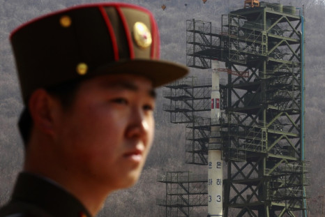 Soldier stands guard in front of Unha-3 rocket at West Sea launch site near Pyongyang