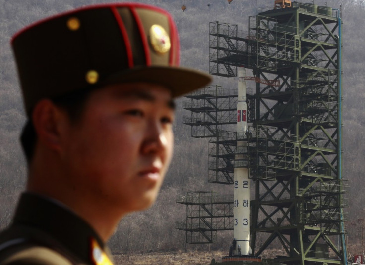 Soldier stands guard in front of Unha-3 rocket at West Sea launch site near Pyongyang