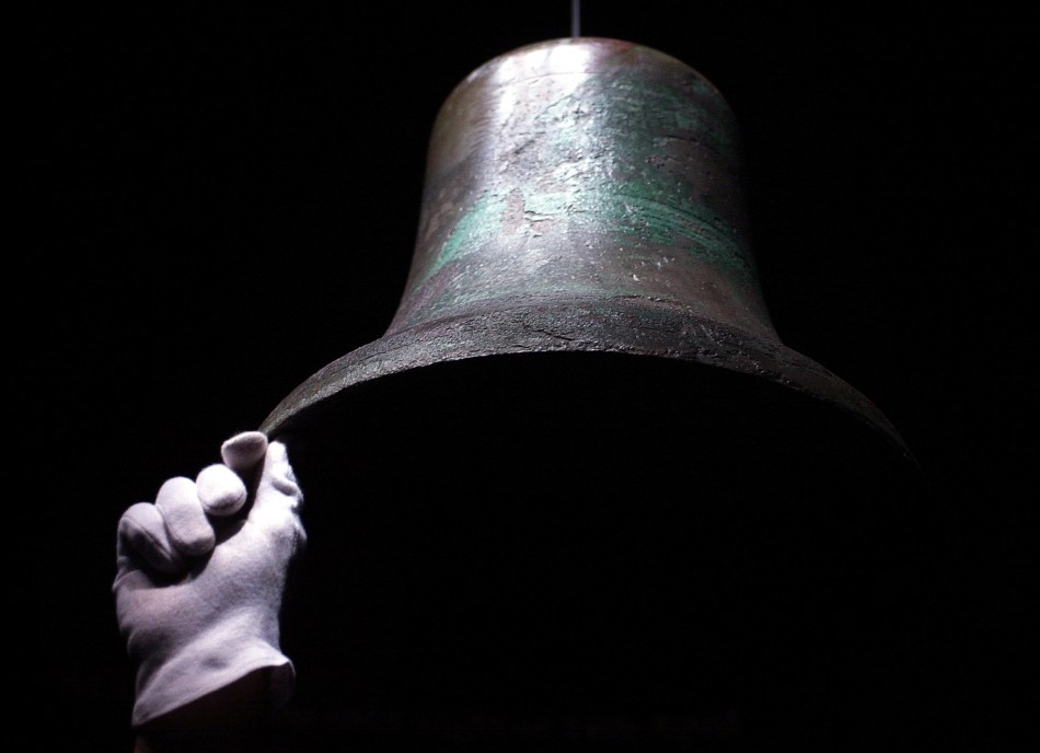 An exhibition worker holds steady the original ships bell which rung out as the Titanic collided with an iceberg on her maiden voyage displayed as part of the TitanicThe Artefact Exhibition at The Science Museum in London
