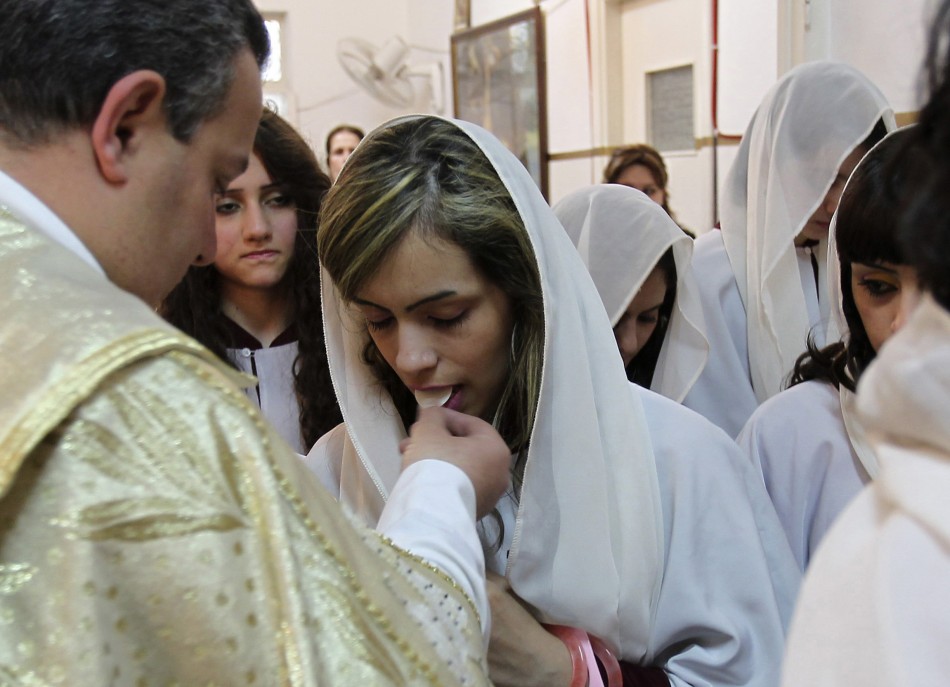 A priest gives communion to an Iraqi Christian during an Easter mass at Chaldean Catholic church in Amman