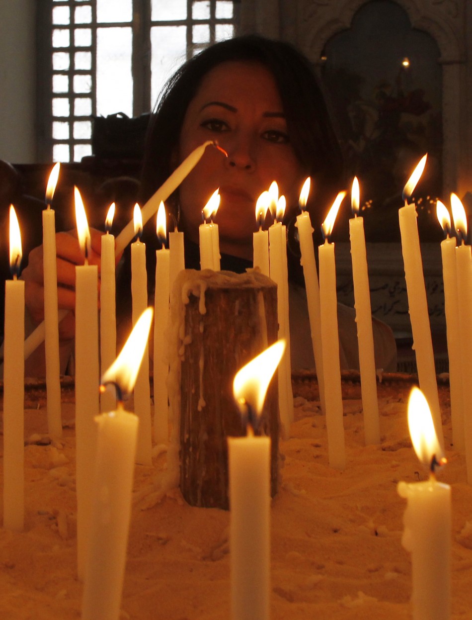 A woman lights a candle as she attends a mass of an Orthodox Easter at the Roman Orthodox patriarchate in Damascus