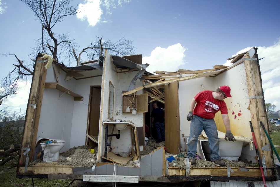 A man picks up debris from a damaged home in Thurman, Iowa