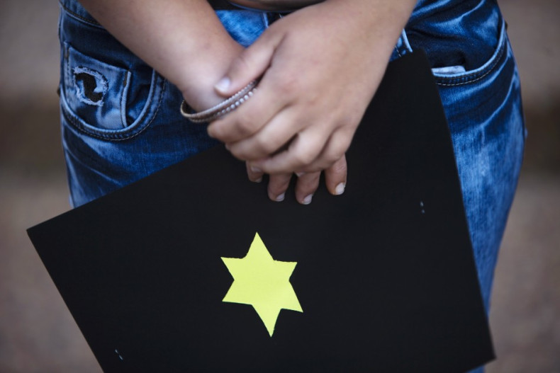 An Israeli holds a card with a yellow star of David outside the German Embassy in Tel Aviv during a demonstration against German author Guenter Grass after the sounding of a siren marking Israel's annual day of Holocaust remembrance April 19, 2012. Israel