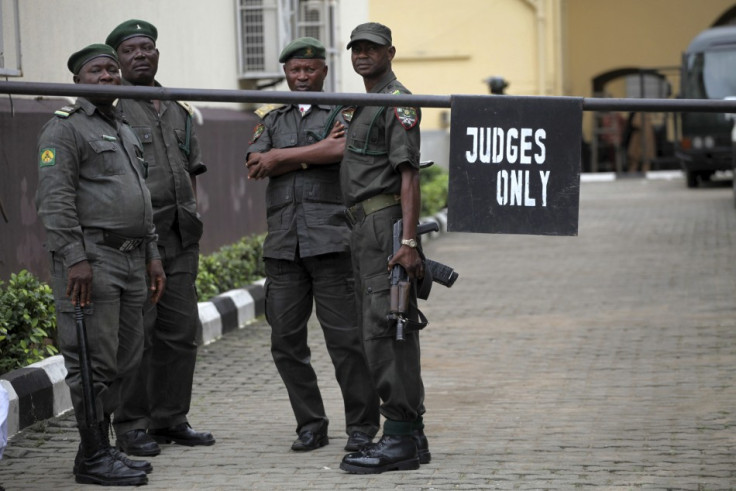 Prison officials wait outside the Lagos high court where Hamza Al-Mustapha is standing trial