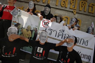 Protesters against Thailand’s lese-majeste laws wear masks and hold pictures of Amphon Tangnoppaku, who has died during whole serving a 20-year sentence for defaming the Queen (Reuters)