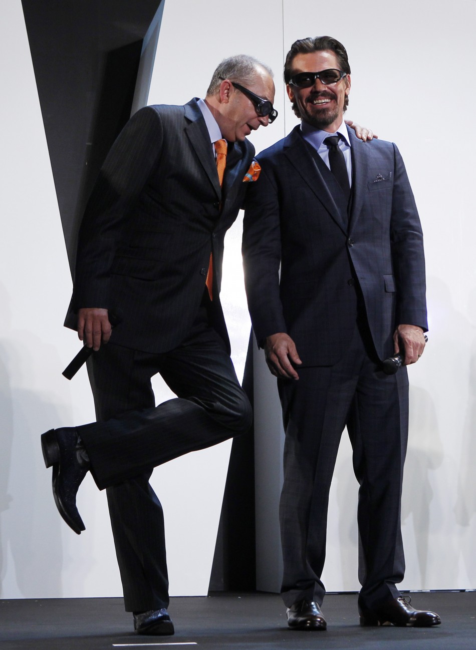Director Barry Sonnenfeld leans on his cast member Josh Brolin to stretch his leg on a stage at a red carpet event in Japan
