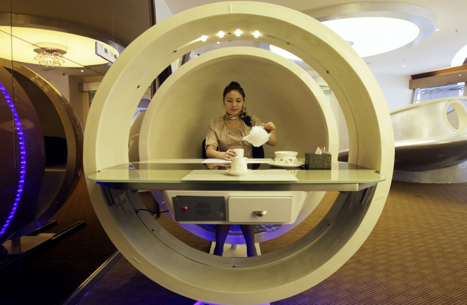 A waitress poses inside an egg-shaped dining booth at an A380 theme restaurant during a media event before its official opening in Chongqing municipality