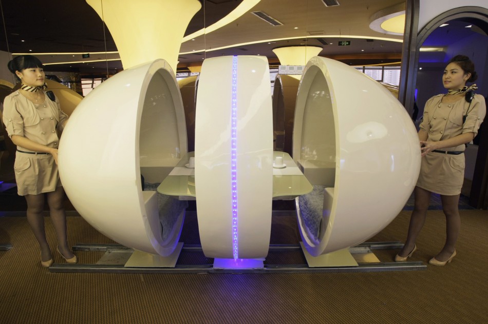 Waitresses reveal an egg-shaped dining-table at an A380 theme restaurant during a media event before its official opening in Chongqing municipality