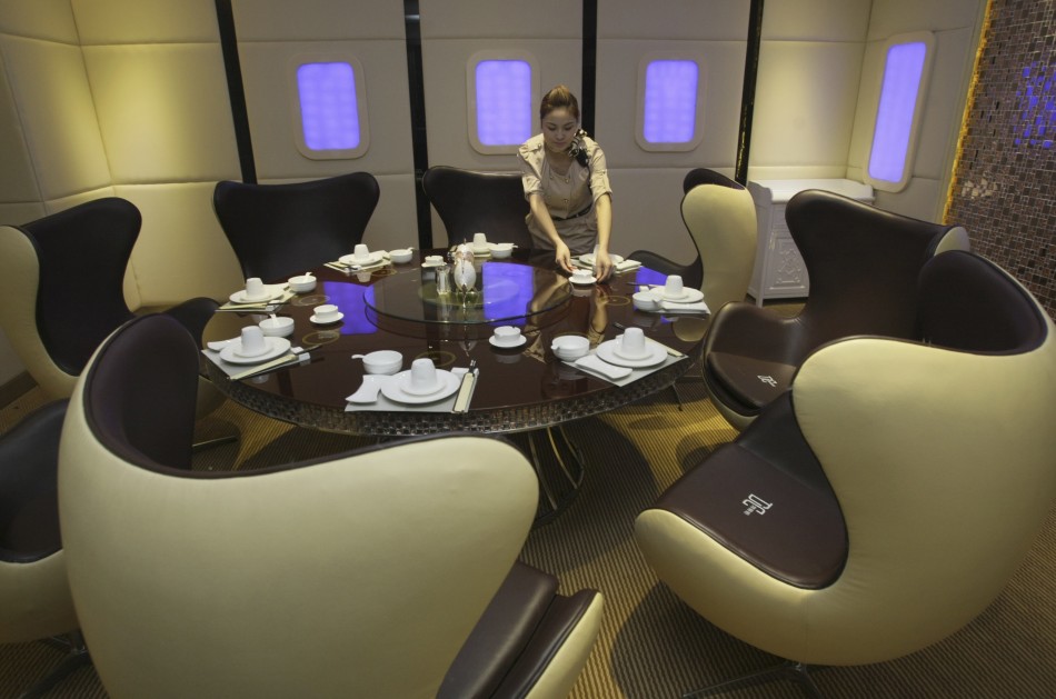 A waitress poses as she arranges a dining table inside a private room of an A380 theme restaurant during a media event before its official opening in Chongqing municipality
